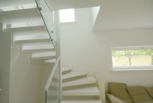 Metalltrepp, kandekonstruktsioon 10x100 mm sik-sak teraslehest, astmed pöögi liimpuidust ja värvitud valgeks. Piirdeks kirgas 12 mm karastatud klaas.