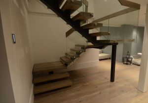 Metallist ühetala trepp, tala 100x150 mm, astmed 77 mm paksusest tamme liimpuidust. Piirdeks karastatud ja lamineeritud 6+6 mm kirgas klaas.